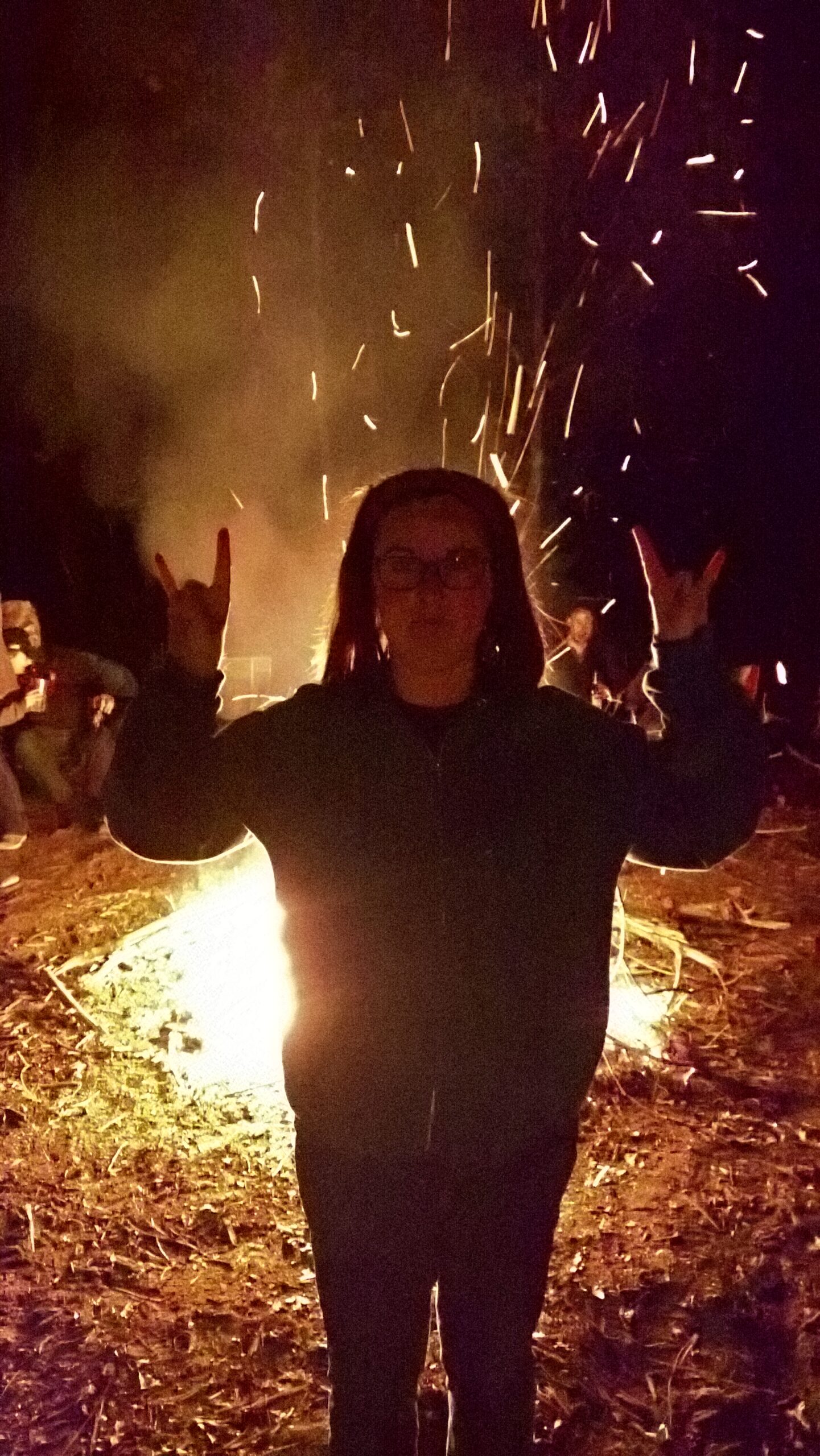 girl with rock and roll sign in front of bonfire