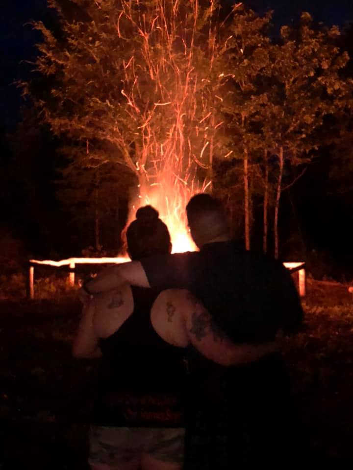 two people arm in arm in front of a bonfire