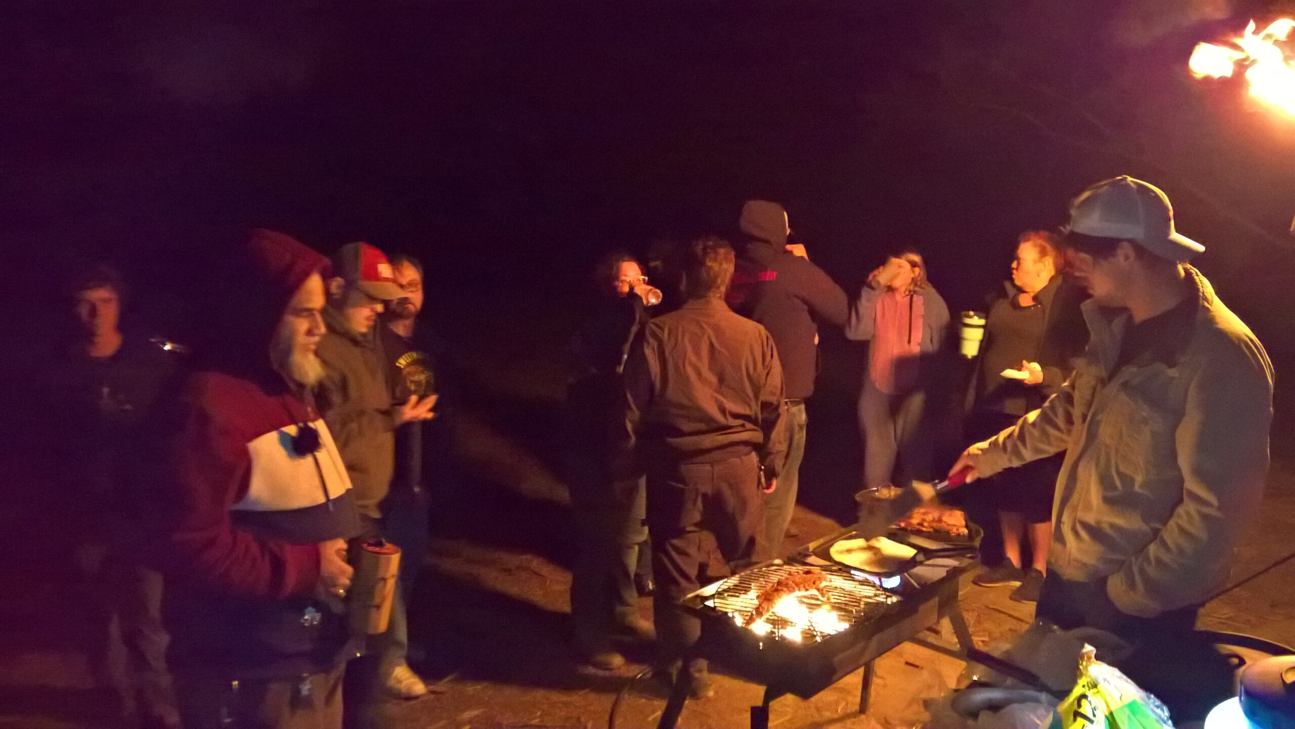 campers cooking food and mingling at night